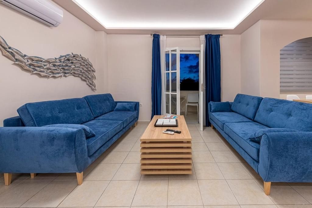 Un soggiorno moderno con due divani blu, un tavolino in legno e un elemento decorativo a parete.