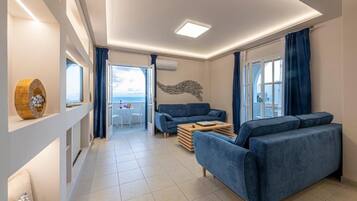 A modern living room with a sofa, a coffee table, and a view of the sea through large windows.