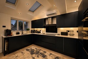 A modern kitchen with dark cabinetry, a central island, and skylights. - Modern 3-Bed, 2-Bath Home | Parking for 3 | Air Conditioning | Rugby (Rugby)