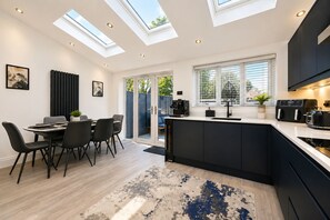 A modern kitchen with skylights, a dining area with chairs, and a large island with appliances. - Modern 3-Bed, 2-Bath Home | Parking for 3 | Air Conditioning | Rugby (Rugby)