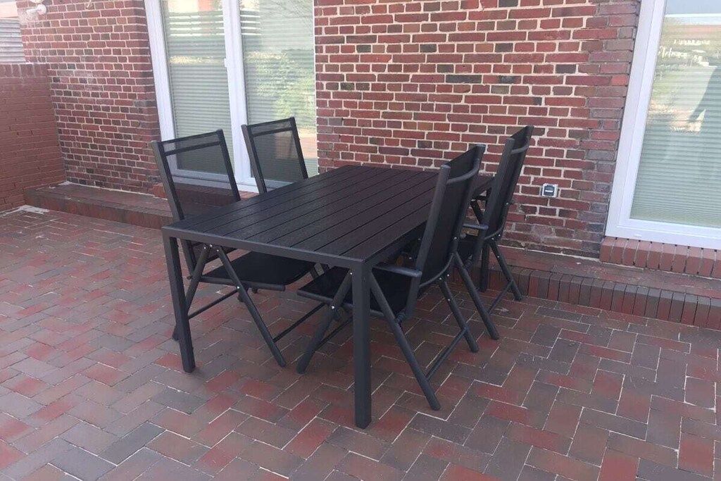 An outdoor patio with a dark wooden table and four chairs.