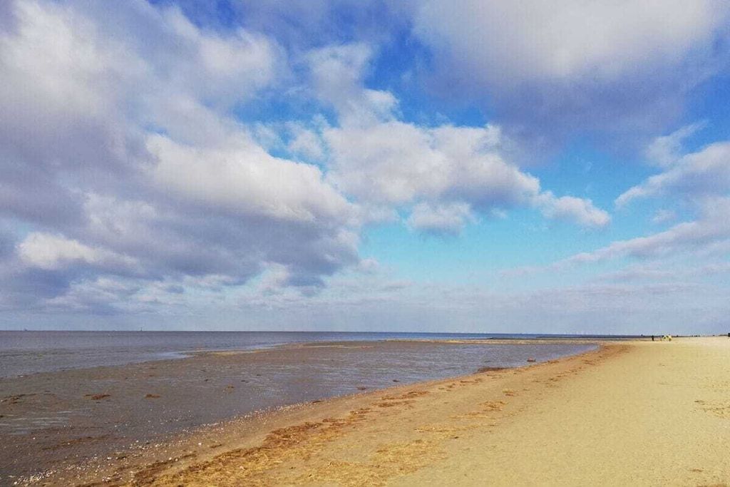 Ein Strand mit breitem Sandstrand und blauem Himmel.