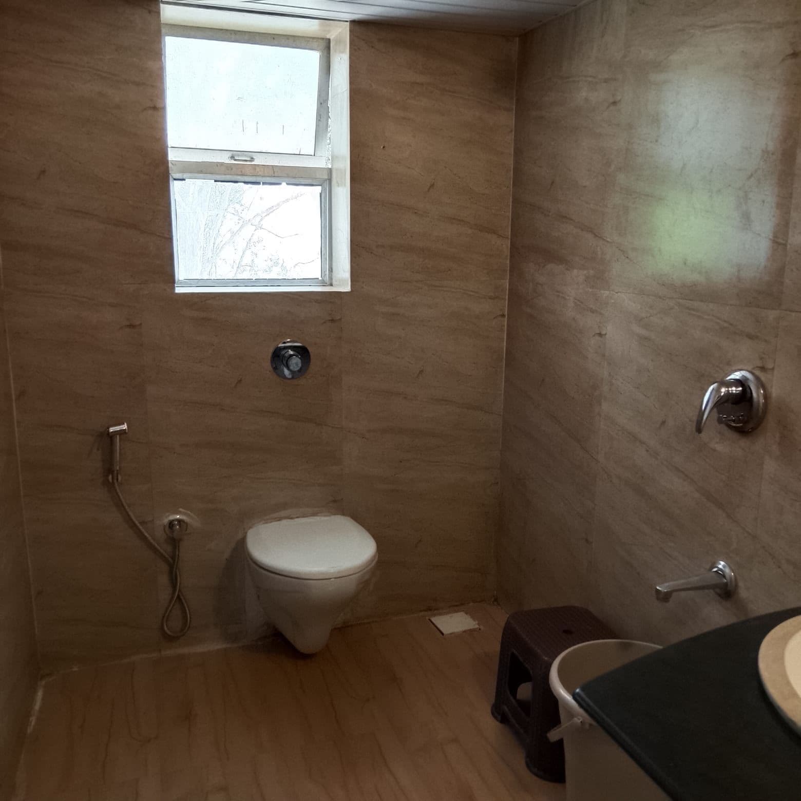 A small bathroom with a toilet, a shower, and a window.