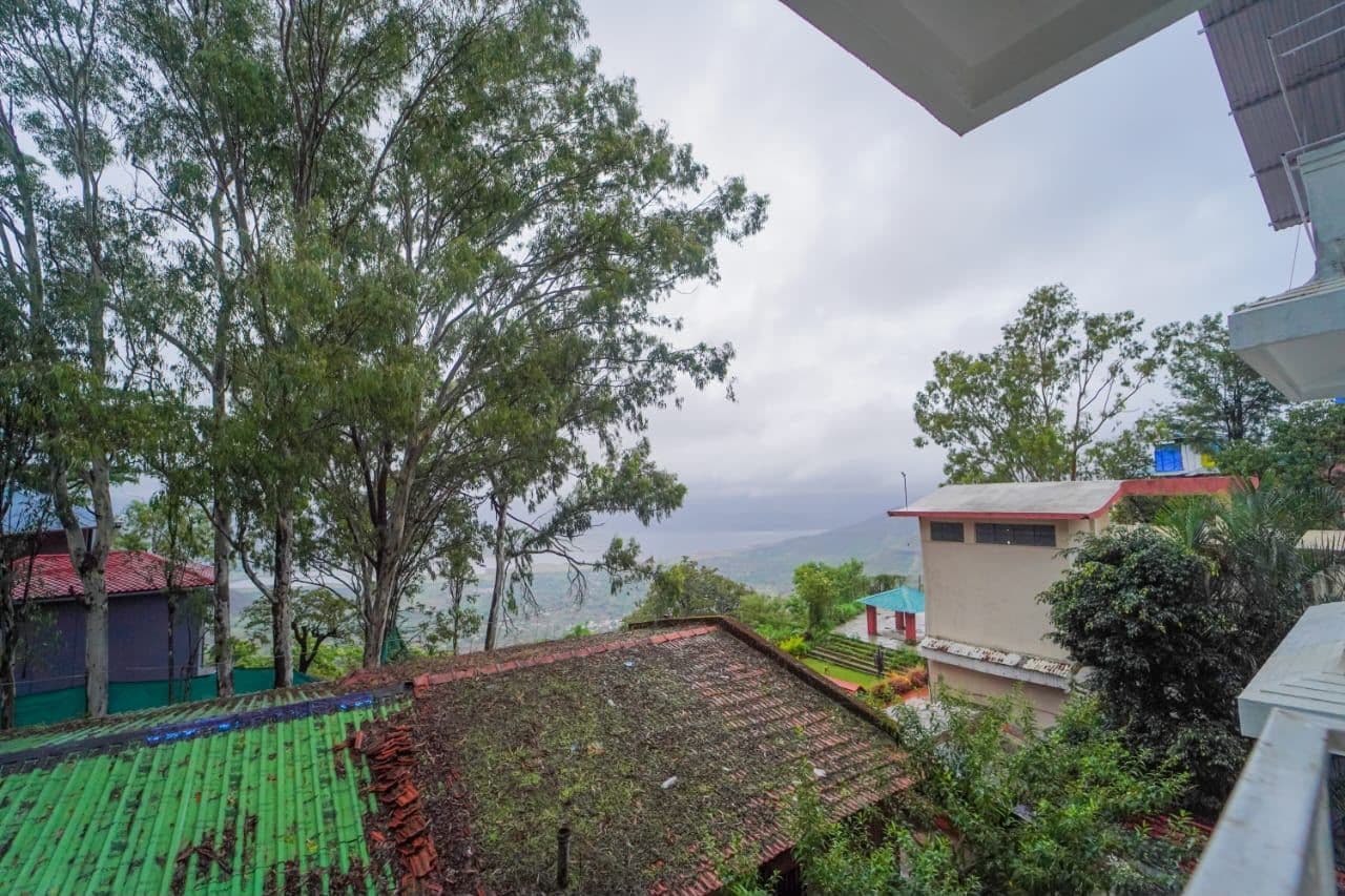 Zona residencial con vista a un valle, casas con techos rojos y una estructura con techo verde.