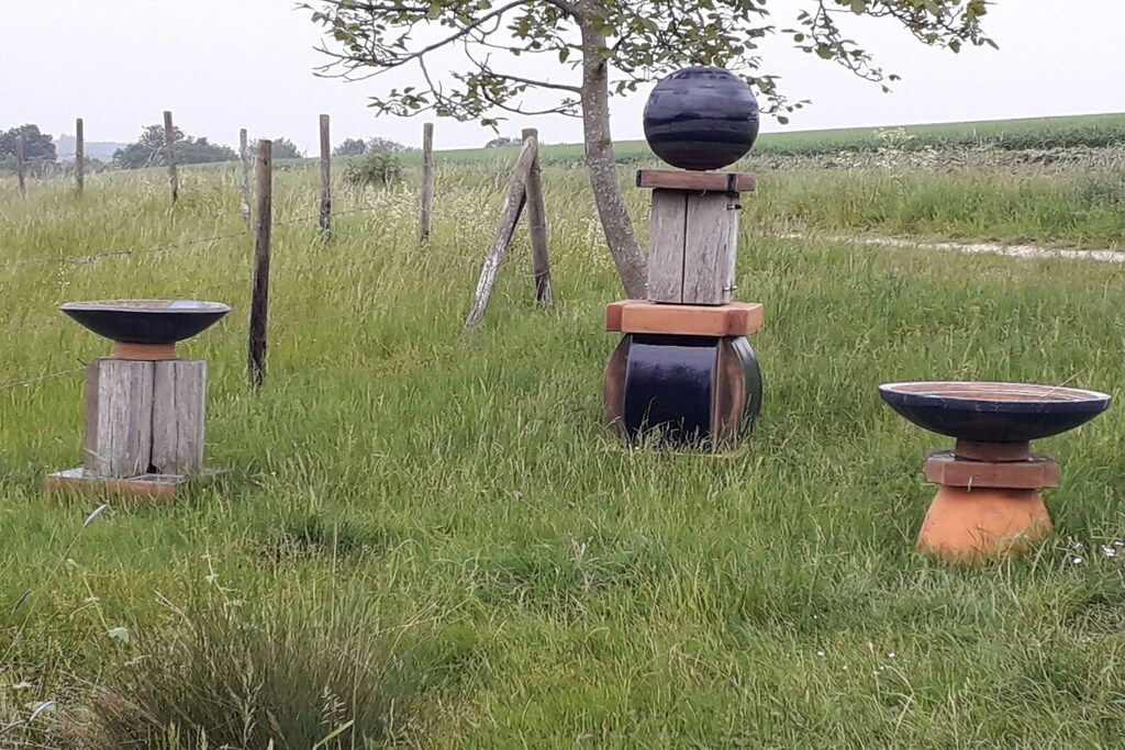 An outdoor setting with three rustic stone structures in a grassy field.