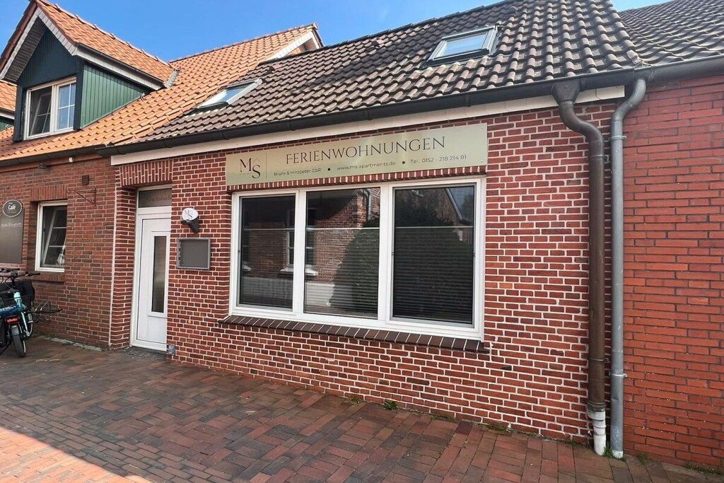 A brick building with a sign reading 'FERIENWOHUNGEN' and a window with blinds.