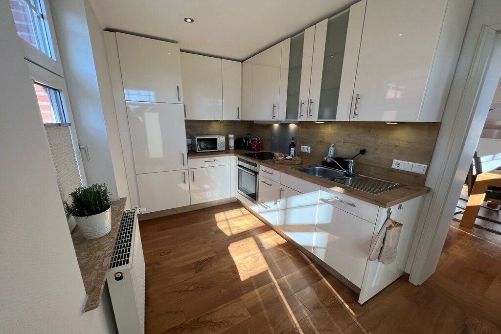 Een moderne keuken met witte kastjes, een houten aanrecht en een ingebouwde oven.