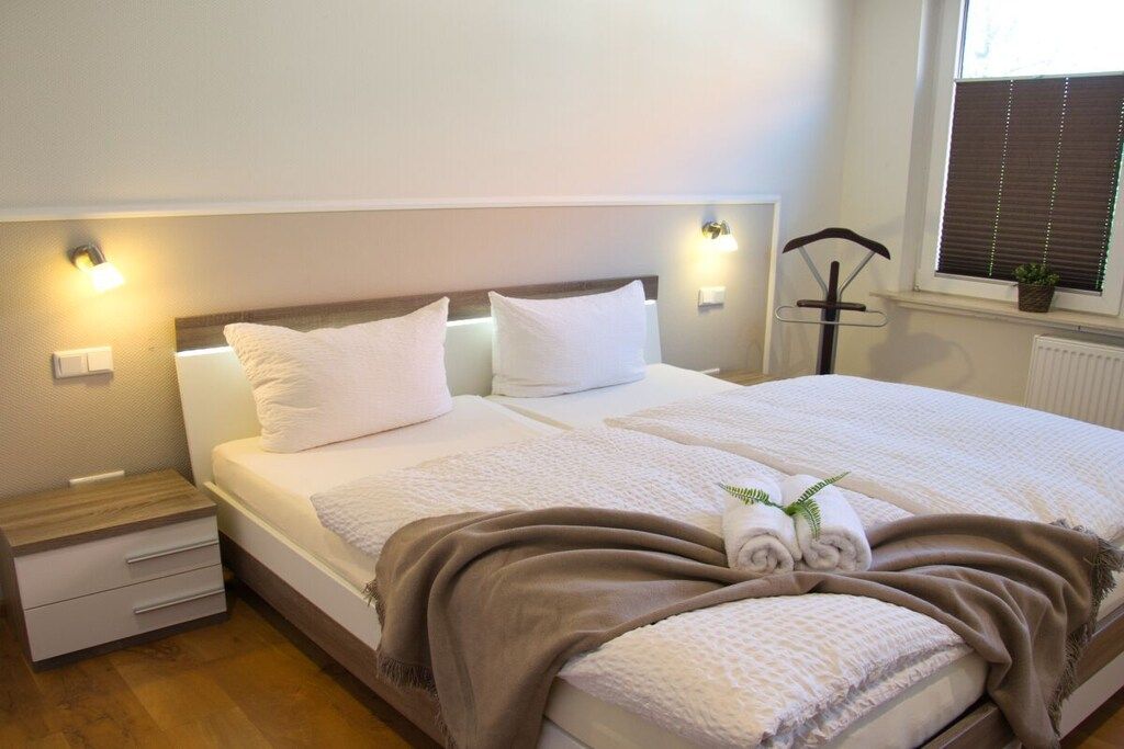 A hotel room with a bed, bedside tables, and a window with blinds.