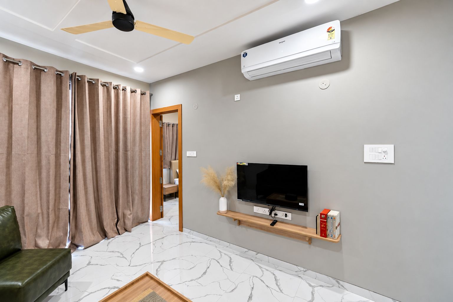 Ein modernes Wohnzimmer mit Fernseher, Deckenventilator und Wandklimaanlage.