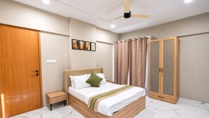 Una habitación de hotel con cama, mesita de noche, armario y ventilador de techo.
