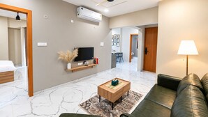 Una sala de estar moderna con un televisor de pantalla plana, una mesa de centro de madera, un sofá de cuero y un ventilador de techo.