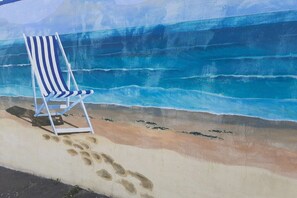 A beach scene with a striped beach chair and footprints leading to it. - Holiday apartment with 1 bedroom (Cuxhaven)