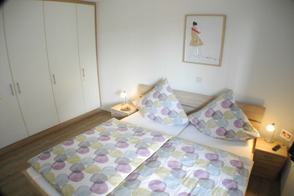 Ein Schlafzimmer mit einem Bett, zwei Nachttischen, einem Schrank und einem Wandbild.