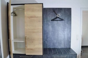 Ein Schrank mit Holztür und schwarzem Einsatz, einer Kleiderstange und einer Schubladeneinheit.