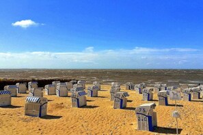 Ein Strand mit zahlreichen Holzgebäuden, vermutlich Strandkörben, die in Reihen angeordnet sind.
