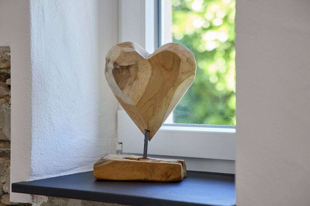 Ein herzförmiges Holzobjekt auf einem Regal in der Nähe eines Fensters.