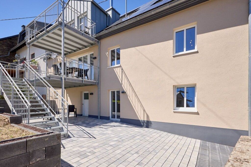 A multi-story building with a staircase leading to an upper floor, a flat roof, and a paved outdoor area.