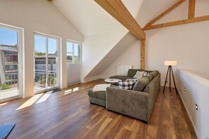 Un dormitorio estilo loft con techo de madera, un sofá verde, una mesita y una lámpara.