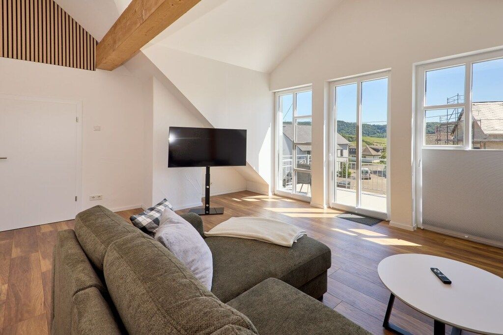 A modern living room with a large window, a flat-screen TV, and a sofa.