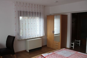 Ein Schlafzimmer mit einem Bett, einem Sessel, einem Kleiderschrank und einer Heizung.