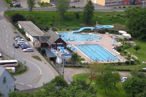 Ein Poolbereich mit mehreren Pools, einem kleinen Gebäude und einem Parkplatz.