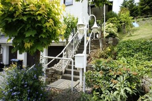 Eine Treppe aus Stein führt zu einem weißen Gebäude mit einem Metallgeländer und zwei weißen Laternen.
