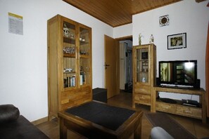 Ein Wohnzimmer mit Holzausstattung, einem Fernseher und einem Sofa.