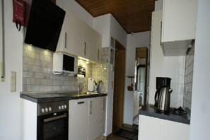 A kitchen with white cabinets, a microwave, a stove, and a coffee maker. - Holiday apartment with 1 bedroom (Treis-Karden)