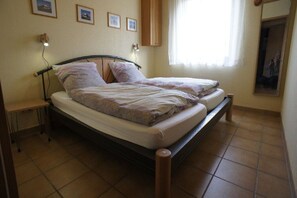 A double bed with a wooden frame, a bedside table, and a wall-mounted lamp. - Holiday apartment with 1 bedroom (Treis-Karden)