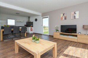 Un salon moderne avec une table basse en bois, un téléviseur et des œuvres d’art accrochées au mur.