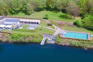 Vue aérienne d’une propriété dotée d’une piscine, d’un quai et d’un bâtiment à toit plat.