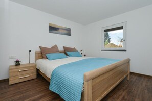 Une chambre à coucher avec un lit en bois, une table de chevet, une fenêtre et un tableau accroché au mur.