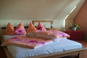 Une chambre à coucher avec un lit, des oreillers, une table de chevet et une commode.