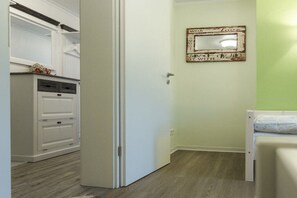 A room with a white wardrobe, a bed with a white headboard, and a wall-mounted mirror. - Holiday apartment with 2 bedrooms (Wernigerode)