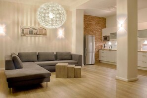 Ein modernes Wohnzimmer mit einem Ecksofa, einem Couchtisch und einer Küchenzeile inklusive Kühlschrank und Mikrowelle.