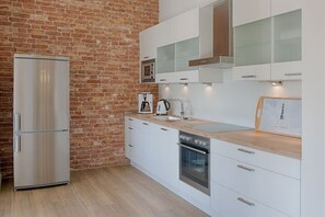 Eine moderne Küche mit Backsteinwand, Edelstahlgeräten und weißen Schränken.