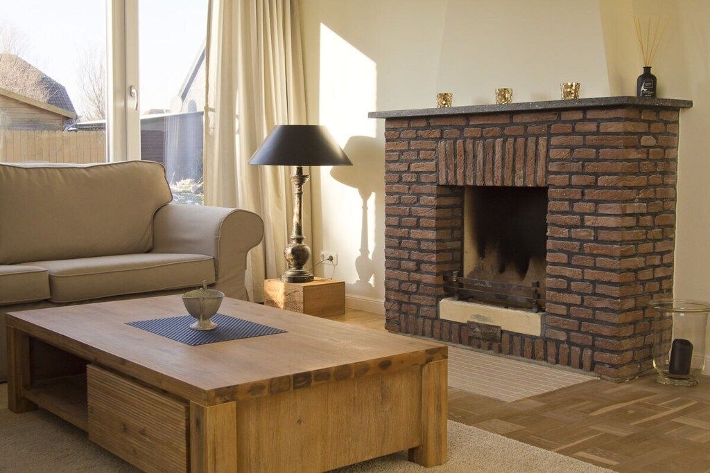 A living room with a sofa, a wooden coffee table, a fireplace with a brick surround, and a lamp.
