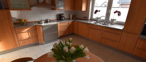A kitchen with wooden cabinets, a stainless steel sink, and a dining table with a vase of flowers.