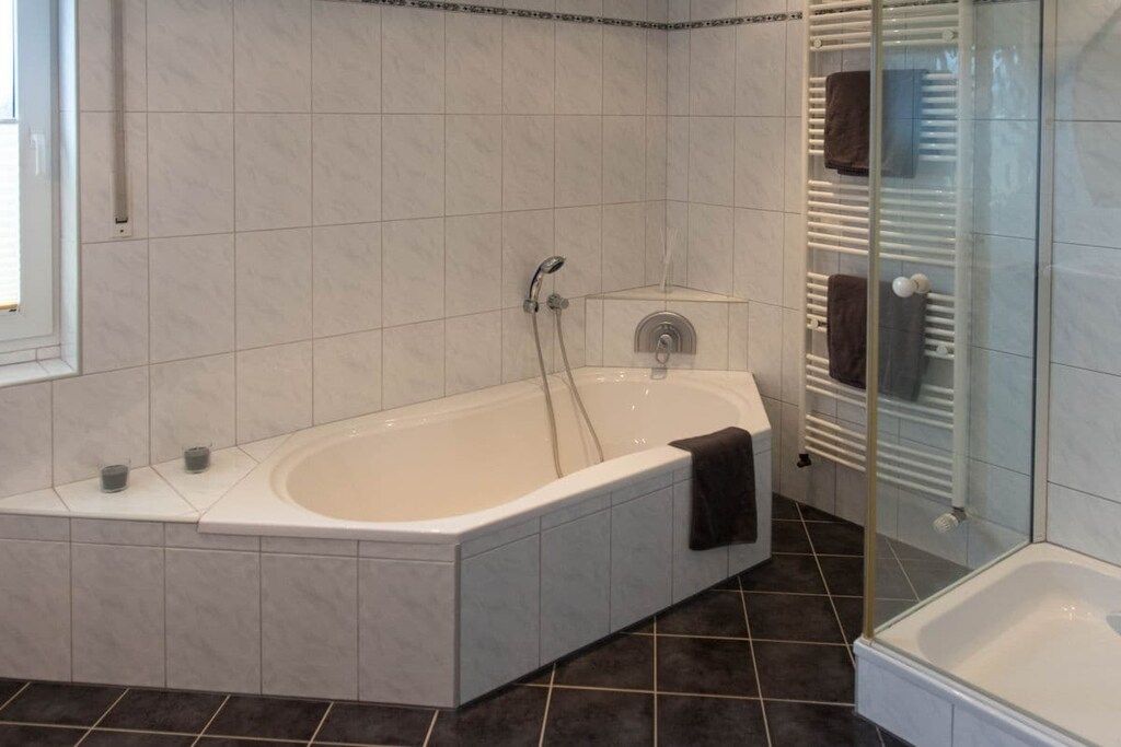 A modern bathroom with a freestanding bathtub, a glass shower enclosure, and a tiled floor.
