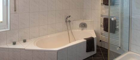 A modern bathroom with a freestanding bathtub, a glass shower enclosure, and a tiled floor.