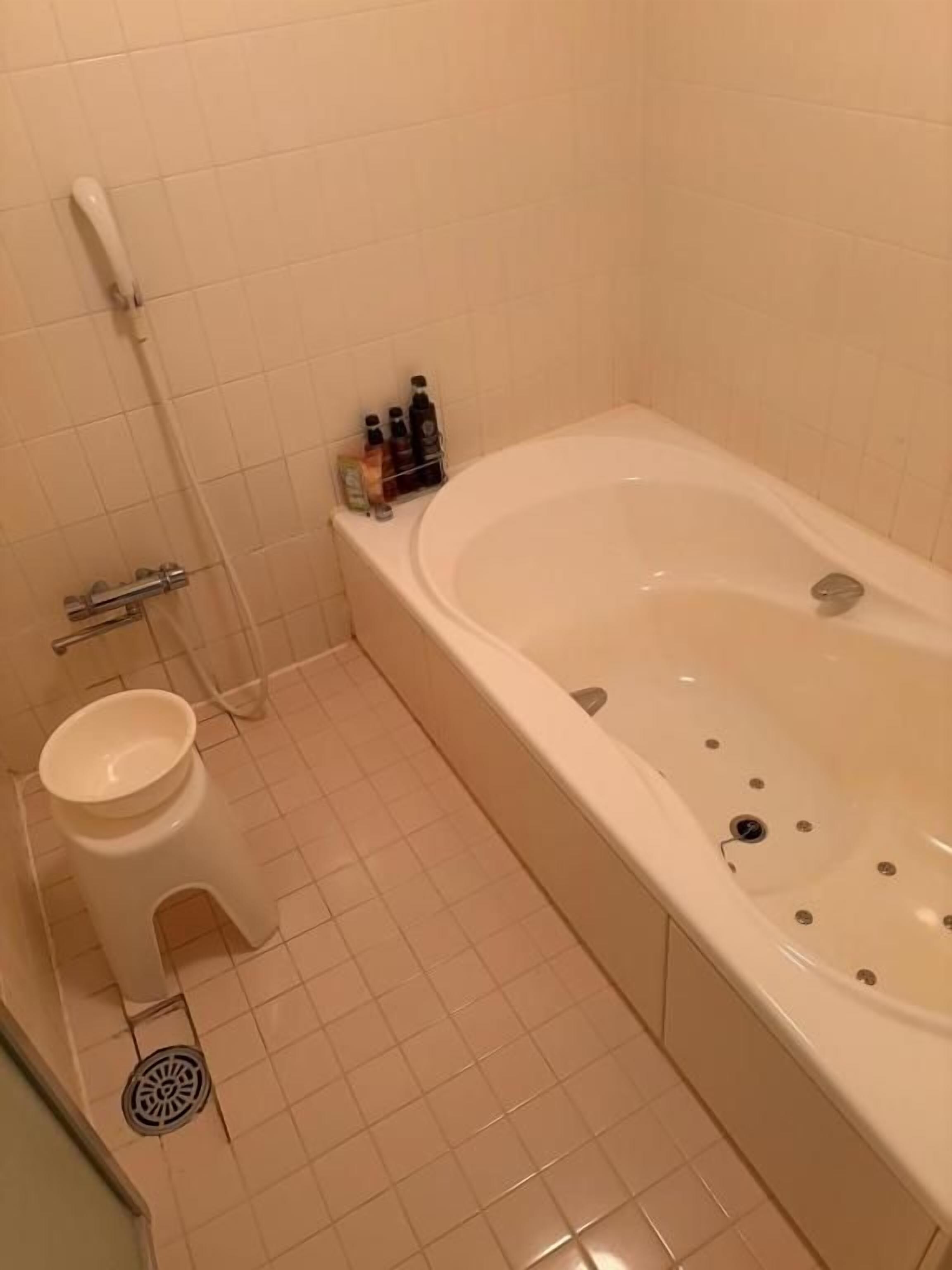 A bathroom with a bathtub, toilet, and a small stool.