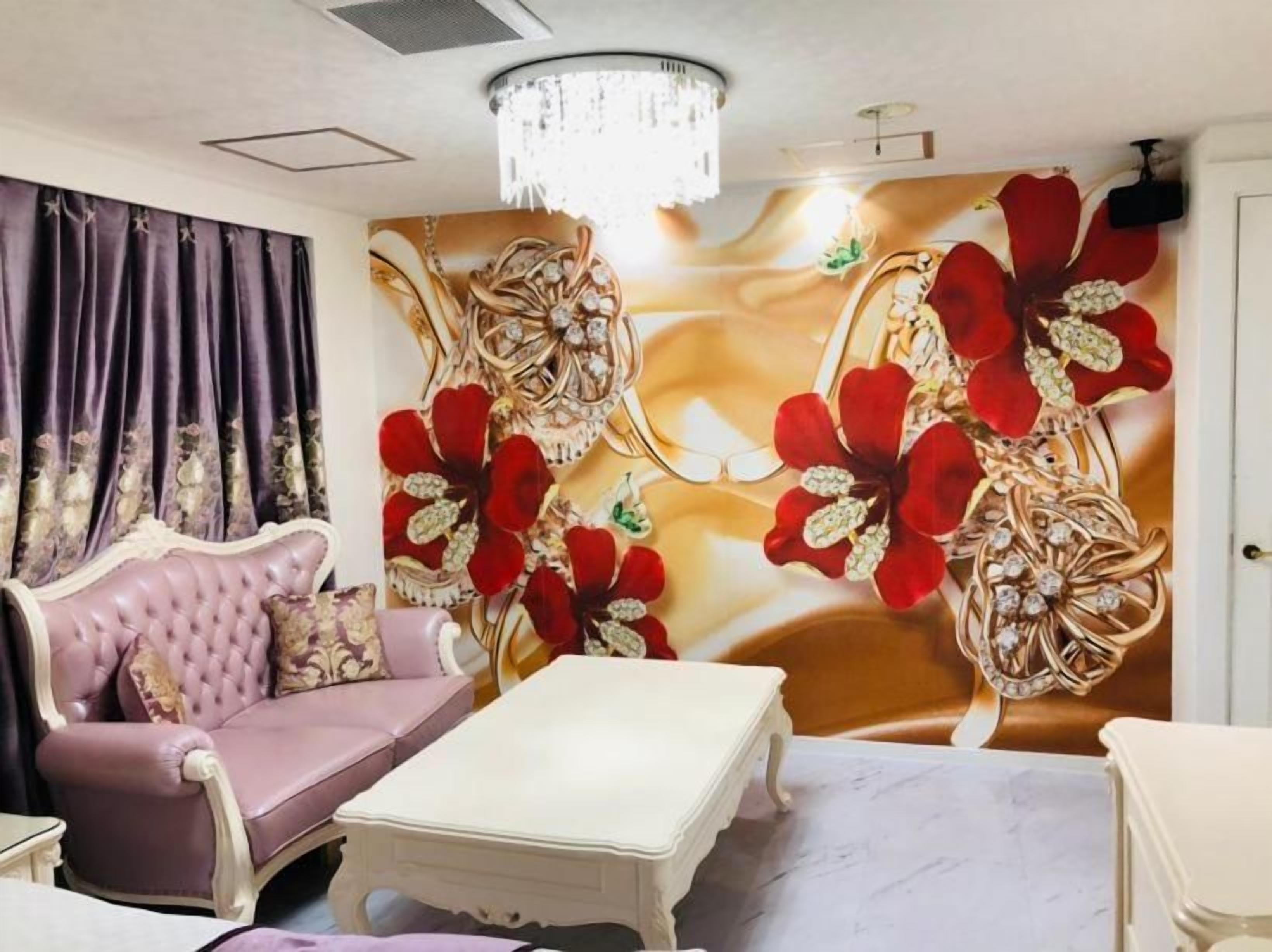 A room with a tufted sofa, a white coffee table, and a wall with floral artwork.