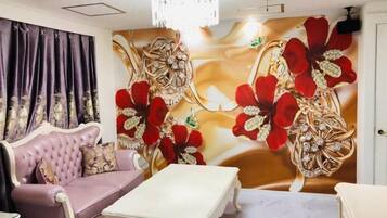 A room with a tufted sofa, a white coffee table, and a wall with floral artwork.