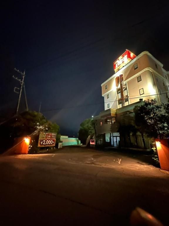 A multi-story hotel building with a brightly lit entrance and a sign indicating a price of ¥2,000.