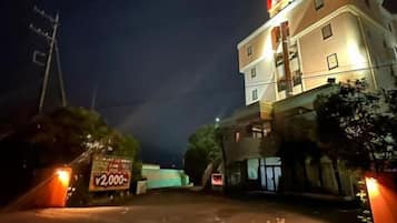 A multi-story hotel building with a brightly lit entrance and a sign indicating a price of ¥2,000.