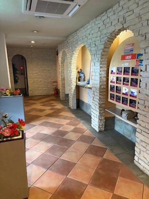 A lobby with a check-in counter, a reception desk, and a display of photos.