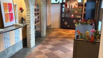 A hallway with a checkered floor, stone arches, a reception desk, and a counter with a floral arrangement.