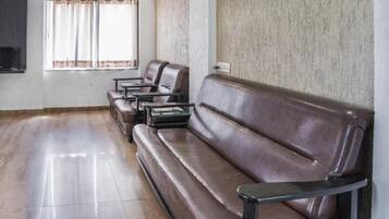 Un área de descanso con sofás y sillones de cuero, un televisor y un ventanal con cortinas.