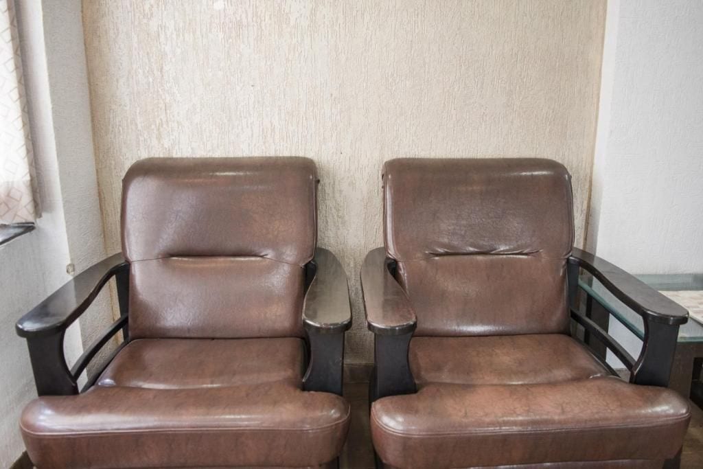 Duas poltronas de couro marrom, com apoio de braço, em frente a uma parede texturizada.