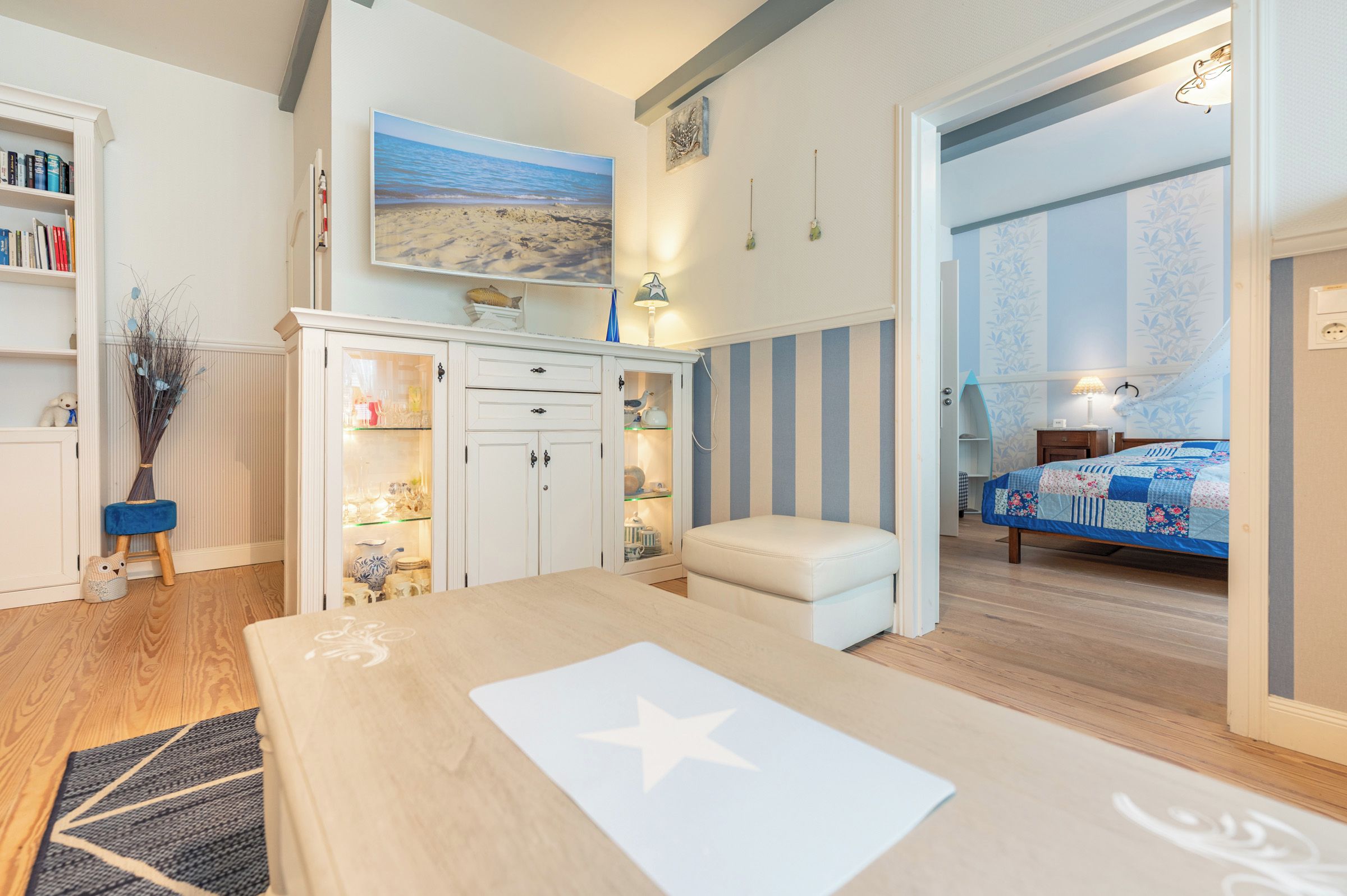 A bedroom with a bed, a desk, and a view of the beach through the window.